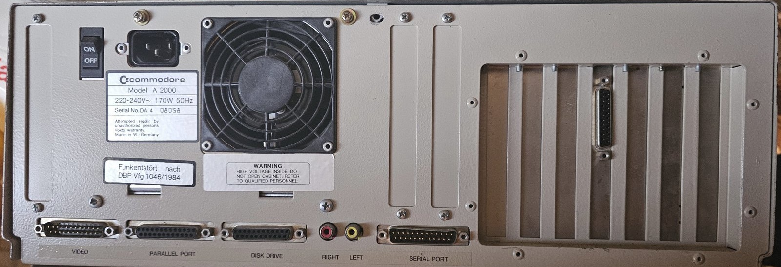 Komplette Rückseite des dokumentierten Commodore Amiga 2000 mit Netzteil, Lüfter, Video-, Parallel-, Disketten-, Audio- und Serial-Anschlüssen sowie Erweiterungsslots