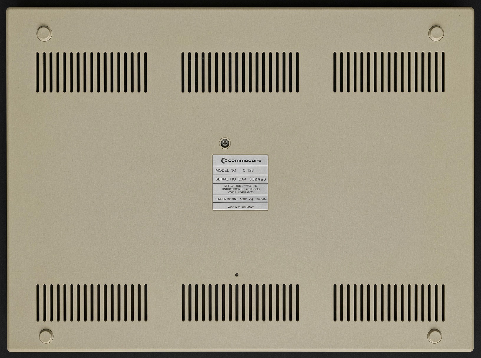 Unterseite des erhaltenen Commodore 128 mit Lüftungsschlitzen und Typenschild